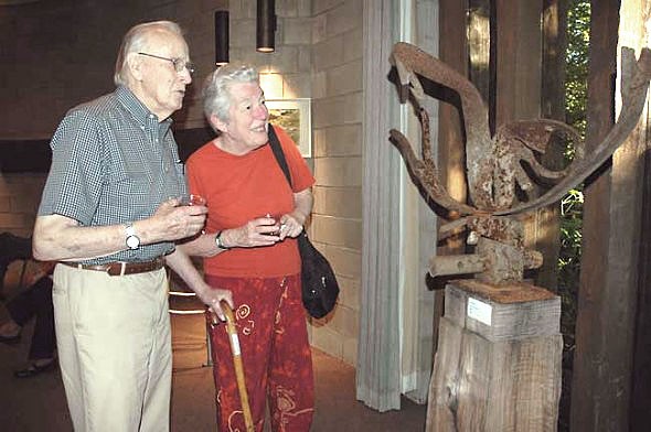Bill Hooper and Jane Baker were among the many villagers who attended the Friday night reception for the art exhibit that features artwork inspired by the Glen. They are looking at "Glen Helen Raptor" by local sculptor Jon Hudson, created from scrap metal found in the Glen. (Photo by Diane Chiddister)