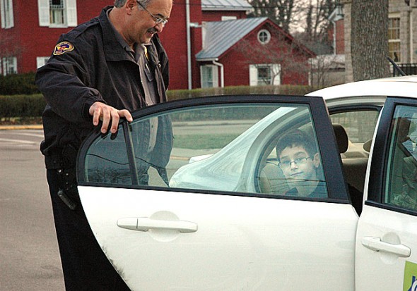 Yellow Springs Police Chief John Grote is retiring at the end of this month after 25 years with the department. He’s shown here at his daily morning duty helping Mills Lawn School kids get out of cars and into the school safely. A reception for Chief Grote, plus two other Village retirees, will take place Thursday, March 29, at 11:30 a.m. in rooms A and B at the Bryan Center.