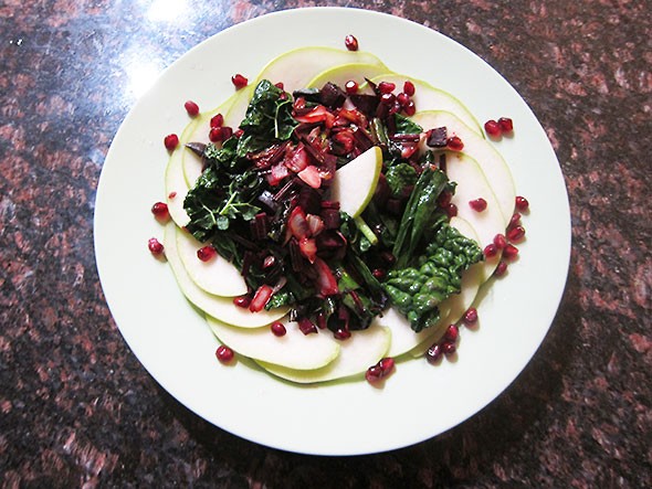 A kale and beet stir fry served on a bed of sliced pear