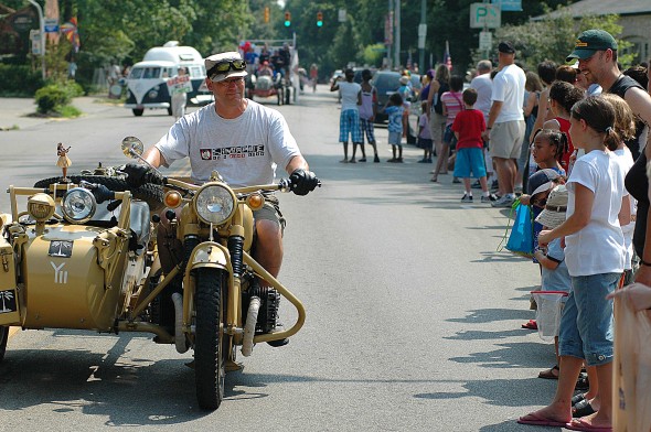 Spectators check out a vintage motorcycle as it drives through town during the annual 4th of July parade. (Photo by Megan Bachman)