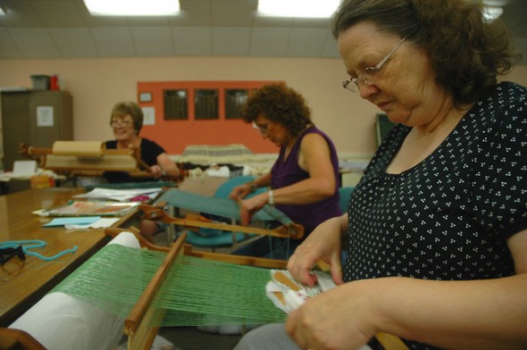 Ruth Flory, right, weaves gift bags from used plastic grocery bags while Cindy Carbone, center, and Debbie Hogue, left, work their looms. (Photo by Megan Bachman)