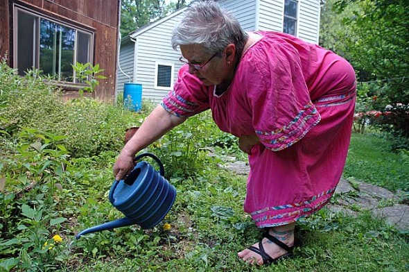 Laurie Dreamspinner used the water from one of the four rain barrels connected to her downspouts to water the marigolds, peas and herbs she grows in her front and side yards. The stormwater reclamation saves her money and the already wet area unneeded runoff. (Photo by Lauren Heaton)