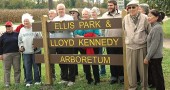 Lloyd Kennedy, second from right, stood at the sign that bears his name during the rededication of Ellis Park, which has been renamed in honor of Kennedy and his long-term commitment to planting trees in the village. (Photo by Lauren Heaton)