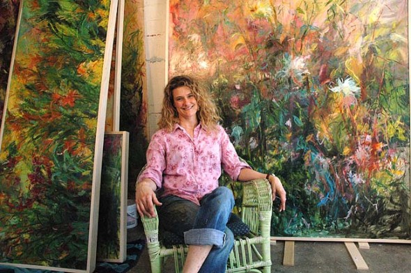 Jennifer Rosengarten sits in front of her many large, colorful oil paintings which are on display at the Dayton Visual Arts Center. (photo by Diane Chiddister)