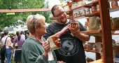 West Freeman browsed the handcrafted pottery of Dick Overman of Cincinnati with his mother, Barbara, at last year’s Art on the Lawn. This year’s art fair, 10 a.m. to 5 p.m. on Saturday, Aug. 10, is Village Artisan’s 30th annual. (Photo by Suzanne Szempruch)