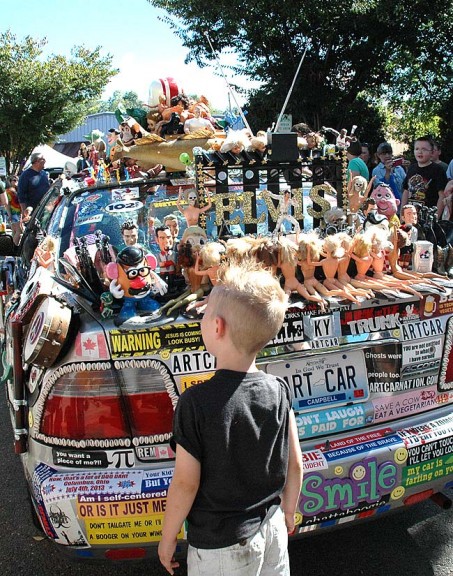 A small Street Fair goer stares down a Mr. Potatohead affixed on the back of the art car. (Photo by Anisa Kline)