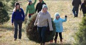 Here, students Cecelia Comerford, left, and Anna Mullin cut and dragged one perfect spruce for an excited Lucy and her family Luke, Sally and Oskar Dennis (behind the tree).