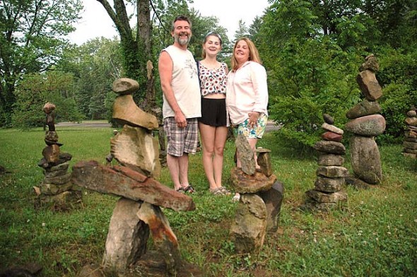 The Village of Yellow Springs Public Art Commission will award Tim and Kelley Callahan, here with their daughter Lucy,  the first Village Inspiration and Design Award, or VIDA, on Friday, June 19, 8 p.m. at the YSAC Gallery. At their home on the corner of Corry Street and Glen View Road, the Callahans have built ever-changing stone piles, or cairns, for the last 20 years. (photo by Lauren Heaton)