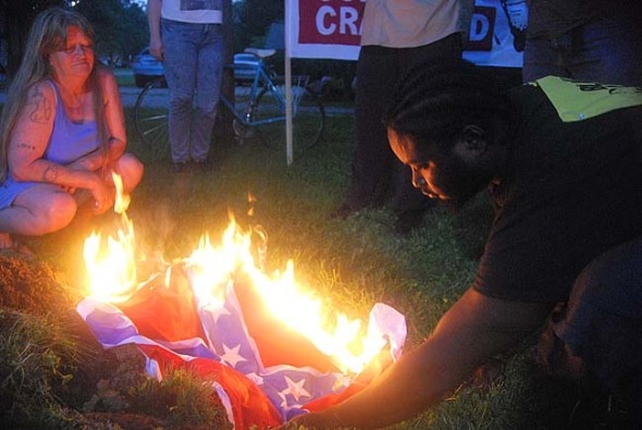As thousands attended last Saturday’s 4th of July fireworks at Gaunt Park, about 30 members of the Greene County Black Lives Matter group burned a Confederate flag in protest of recent church burnings, the Charleston massacre of nine African Americans, and the police shooting last year of John Crawford in the Beavercreek Walmart. Shown above is group member Talis Gage. (Photo by Aaron Zaremsky)