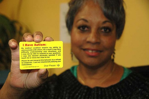 Mijanou Marretta-Lewis, a Yellow Springs resident and mother of two autistic boys, holds a card designed to facilitate easier interactions between people with autism and police. The cards explain why the bearer may have trouble understanding the situation, as police may not be aware of the sensitivities of people with autism. The cards are available at the Yellow Springs Police Department. (photo by Suzanne Szempruch)