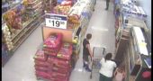 A video still showing John Crawford III, at the far end of the aisle, and shopper Angela Williams and her two children in the foreground. The still is from a Walmart surveillance video from the night of Aug. 5, 2014. (From Walmart security cameras, Youtube)