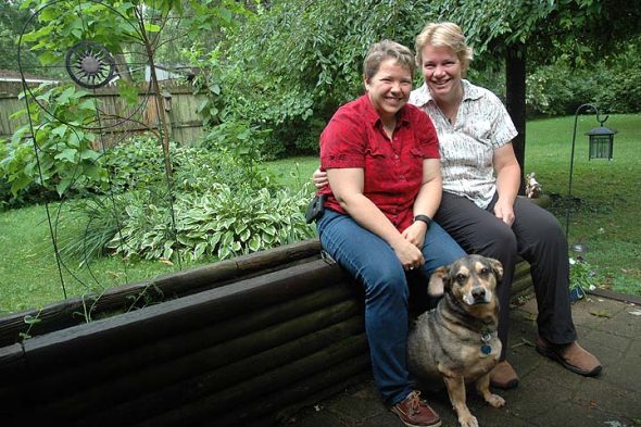 Lori Collins-Hall and Chris Burgher are shown here with their dog, Snickers, in the backyard of their Gardendale Drive home. The two moved to Yellow Springs two years ago from upstate New York after Collins-Hall was offered the job of vice president of academic affairs at Antioch College, where she is now provost. (Photo by Diane Chiddister)