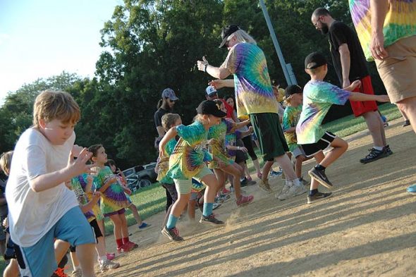 Last Friday, longtime Perry League T-ball coach Jimmy Chesire, center, gave the signal that started a herd of t-ballers stampeding towards the light pole to do stretches and warm-ups for the final “1,000 strikes” of the summer at last year's final night of T-ball. (Photo by Isaac Delamatre)