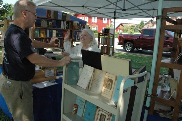 The 36th Annual Yellow Springs Book Fair takes place on Saturday, Aug. 20, from 8 a.m. to 4 p.m. at Mills Lawn School grounds. Shown above, Blue Jacket Books owner Laurence Hammar is shown at last year's fair with villager Anne Johnson.