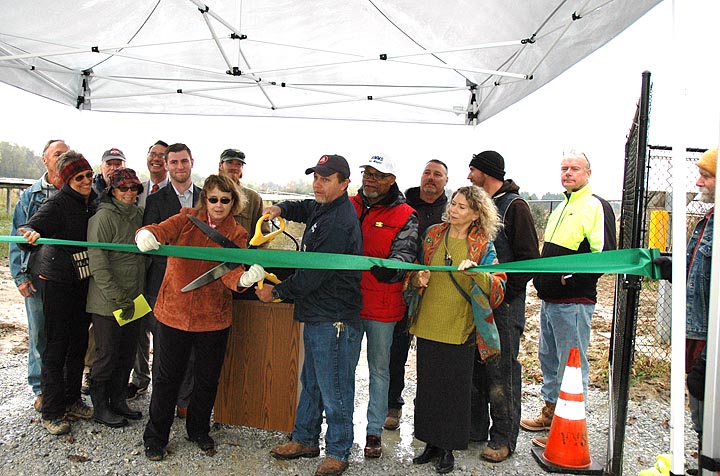 Pictured here in the first row are, from left, Village Manager Patti Bates, Superintendent of Electricity and Water Distribution Johnnie Burns (with big scissors), Council member Jerry Simms and Council President Karen Wintrow. Other Council members and project collaborators are also pictured. (Photo by Audrey Hackett)
