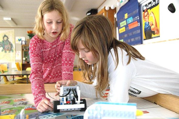 Mills Lawn fourth-graders Malayna Buster, left, and Hannah Parker adjust a robot named Bratwurst, which they helped program as part of their FIRST Lego League after-school team. The girls are members of one of two local 10-member teams that will be competing in a regional tournament Sunday, Dec. 10, being hosted by YS High School junior Alex Ronnebaum at the high school. (photo by Carol Simmons)