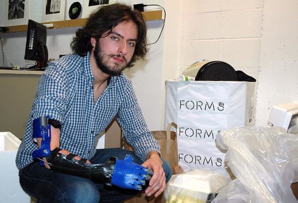 First-year Antioch College student Aaron Westbrook is the founder and CEO of Form5 Prosthetics, a company that makes prosthetic limbs, like the one he’s wearing, from recycled plastic. Westbrook is pictured in his lab space at Antioch with some of the plastic he collected from the local community during a recent plastics drive. (Photo by Audrey Hackett)