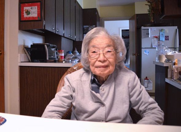 Toshiko Asakawa sits in the kitchen of her President Street home. On the wall behind her is a drawing done by one of her grandchildren, who is now an adult. On May 9, Asakawa will celebrate her 100th birthday. (Photo by Lauren “Chuck” Shows)