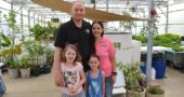 Kimball and Stephanie Osborne, with their children, Elli, left, and Alina, in the lush greenhouse at Oasis Aqua Farms in Beavercreek Township last month, before the tornado hit their property. (Photo by Megan Bachman)