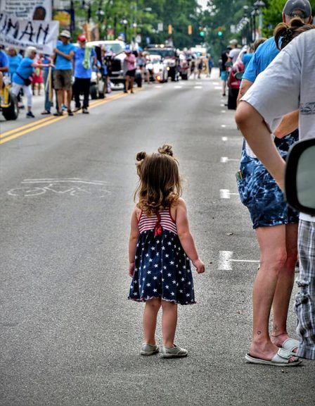 A tiny holiday celebrant watched with fascination as this year’s Fourth of July parade passed down Xenia Avenue. The holiday fell between two other big days for the village: the Pride march and Springsfest. (Photo by Kathleen Galarza)