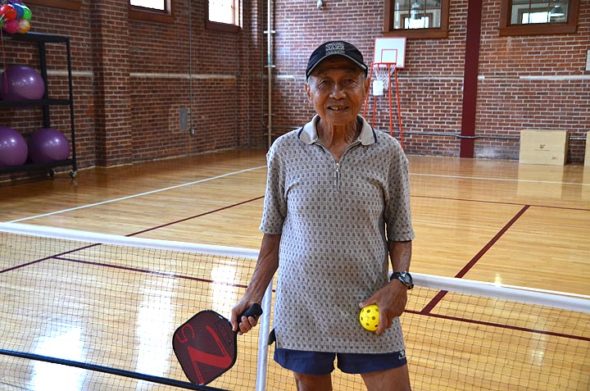 Longtime villager Tjioe Kwan, 78, came home from the National Senior Games in Albuquerque last month with a gold medal in pickleball. He plays locally at several gyms, including the Wellness Center at Antioch College, where he’s pictured on a pickleball court. (Photo by Audrey Hackett)