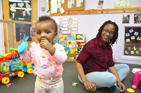 The Yellow Springs Community Children’s Center now enrolls infants aged six weeks to 17 months. The infant program at the almost 75-year-old local nonprofit opened in November, with four infants so far, including Zsa’Lynn, 10 months, who loves to dance and chew. Looking on is lead teacher Aille Turner, an experienced infant and toddler caregiver. (Photo by Audrey Hackett)